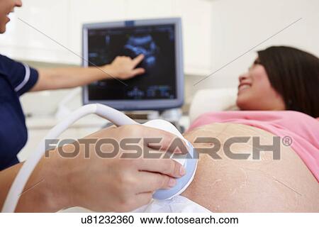 Stock Image - Pregnant Woman And Partner Having 4D Ultrasound Scan. Fotosearch