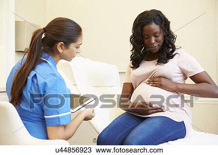 Stock Image - Pregnant Woman Being Given Ante Natal Check By Nurse. Fotosearch