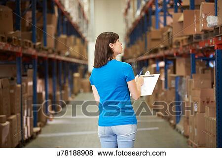 Stock Photo - Rear View Of Female Worker In Distribution Warehouse. Fotosearch