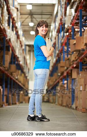 Stock Photo - Rear View Of Female Worker In Distribution Warehouse. Fotosearch