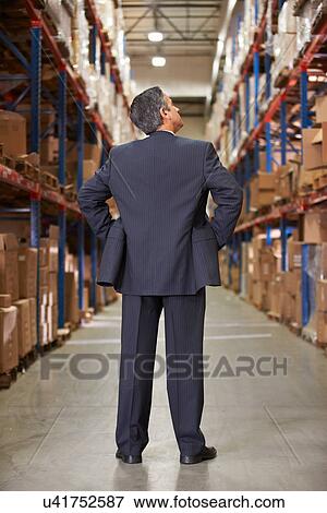 Stock Photo - Rear View Of Manager In Warehouse. Fotosearch