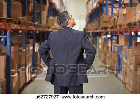 Stock Photo - Rear View Of Manager In Warehouse. Fotosearch