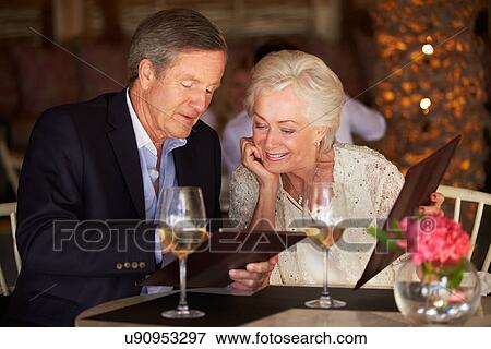 Stock Photo - Senior Couple Choosing From Menu In Restaurant. Fotosearch