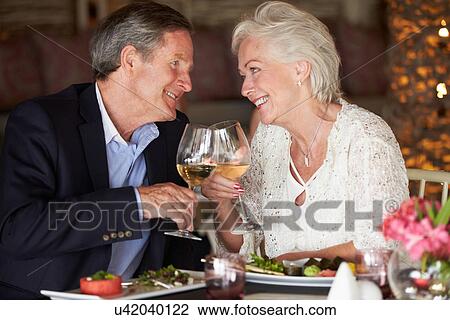 Stock Image - Senior Couple Enjoying Meal In Restaurant. Fotosearch