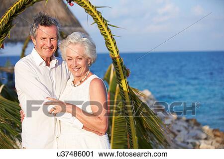 Stock Image - Senior Couple Getting Married In Beach Ceremony. Fotosearch