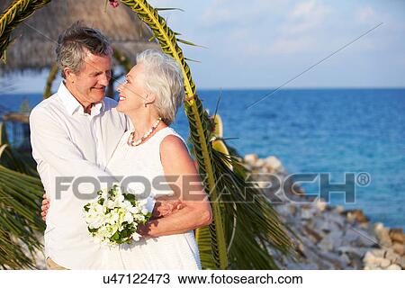 Stock Image - Senior Couple Getting Married In Beach Ceremony. Fotosearch