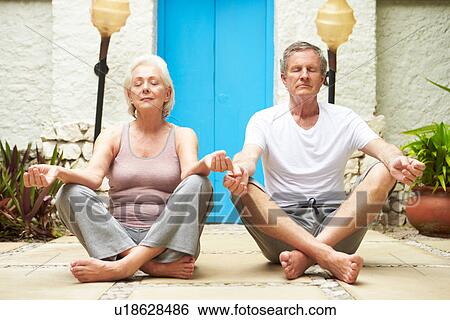 Stock Photograph - Senior Couple Meditating Outdoors At Health Spa. Fotosearch
