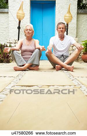 Stock Photograph - Senior Couple Meditating Outdoors At Health Spa. Fotosearch