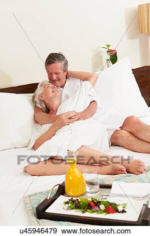 Stock Photo - Senior Couple Relaxing In Hotel Room Wearing Robes. Fotosearch