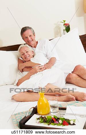 Stock Photo - Senior Couple Relaxing In Hotel Room Wearing Robes. Fotosearch