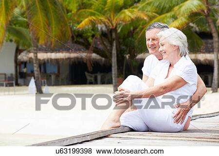 Stock Photo - Senior Couple Sitting On Wooden Jetty. Fotosearch