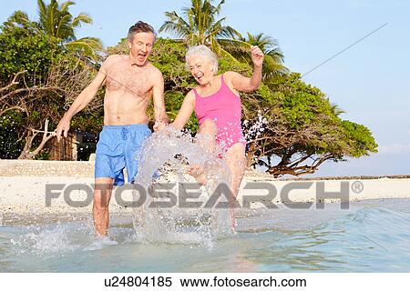 Senior Couple Splashing In Sea On Tropical Beach Holiday View Large Photo Image Stock Photography - Senior Couple Splashing In Sea On Tropical Beach Holiday. Fotosearch