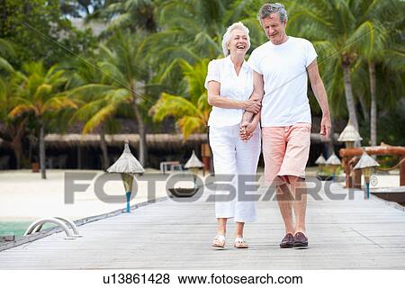 Stock Photo - Senior Couple Walking On Wooden Jetty. Fotosearch