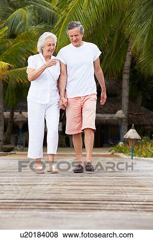 Stock Photo - Senior Couple Walking On Wooden Jetty. Fotosearch