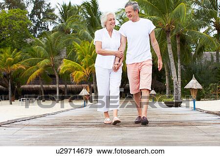 Stock Photo - Senior Couple Walking On Wooden Jetty. Fotosearch