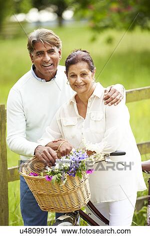 Picture - Senior Indian Couple On Cycle Ride In Countryside. Fotosearch