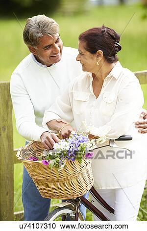 Stock Image - Senior Indian Couple On Cycle Ride In Countryside. Fotosearch