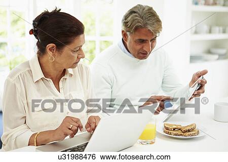 Senior Indian Couple Using Laptop And Digital Tablet At Home View Large Photo Image Stock Photograph - Senior Indian Couple Using Laptop And Digital Tablet At Home. Fotosearch