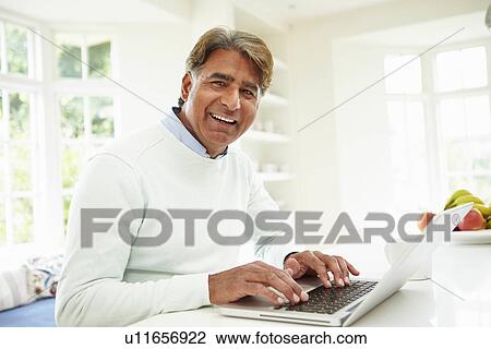 Stock Image - Senior Indian Man Using Laptop At Home. Fotosearch