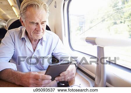 Senior Man Reading E Book On Train Journey View Large Photo Image Stock Photo - Senior Man Reading E Book On Train Journey. Fotosearch