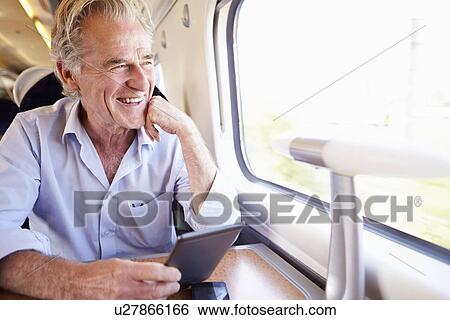 Senior Man Reading E Book On Train Journey View Large Photo Image Stock Photograph - Senior Man Reading E Book On Train Journey. Fotosearch
