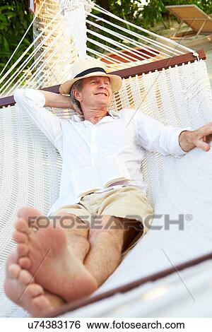 Stock Photograph - Senior Man Relaxing In Beach Hammock. Fotosearch