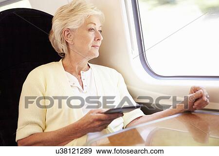 Stock Photo - Senior Woman Reading E Book On Train Journey. Fotosearch