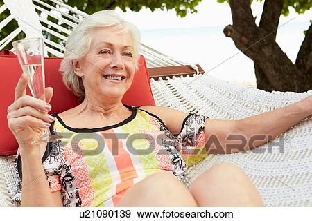 Senior Woman Relaxing In Beach Hammock With Champagne View Large Photo Image Stock Photo - Senior Woman Relaxing In Beach Hammock With Champagne. Fotosearch