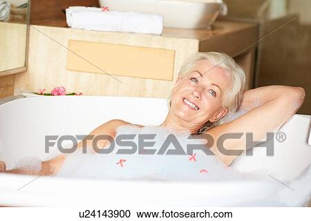 Stock Image - Senior Woman Relaxing In Bubble Bath . Fotosearch
