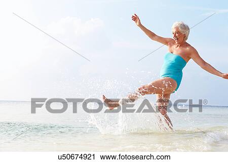 Senior Woman Splashing In Sea On Beach Holiday View Large Photo Image Stock Image - Senior Woman Splashing In Sea On Beach Holiday. Fotosearch