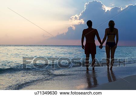 Silhouette Of Couple Walking Along Beach At Sunset View Large Photo Image Stock Image - Silhouette Of Couple Walking Along Beach At Sunset. Fotosearch