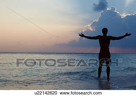 Silhouette Of Man With Outstretched Arms On Beach At Sunset View Large Photo Image Stock Image - Silhouette Of Man With Outstretched Arms On Beach At Sunset. Fotosearch