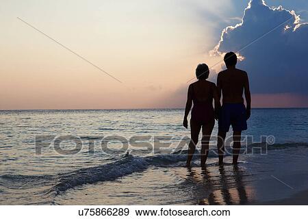 Silhouette Of Senior Couple Walking Along Beach At Sunset View Large Photo Image Stock Photo - Silhouette Of Senior Couple Walking Along Beach At Sunset. Fotosearch