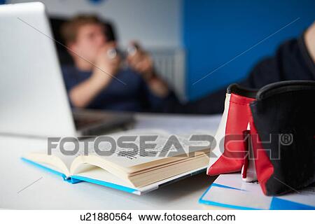 Picture - Teenage Boy Playing Video Game Instead Of Studying. Fotosearch
