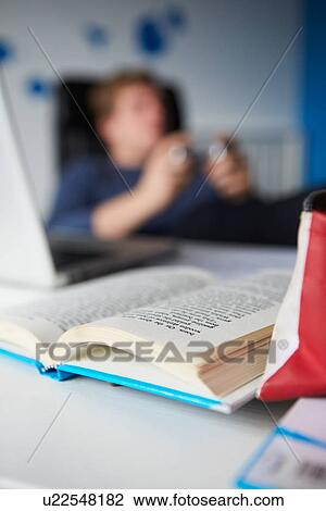 Stock Image - Teenage Boy Playing Video Game Instead Of Studying. Fotosearch