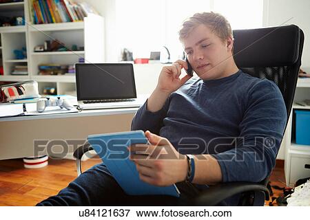 Teenage Boy Using Digital Tablet And Mobile Phone In Bedroom View Large Photo Image Stock Photo - Teenage Boy Using Digital Tablet And Mobile Phone In Bedroom. Fotosearch