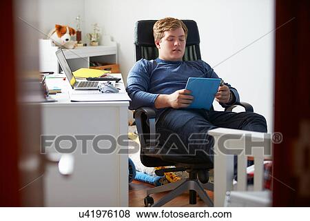 Teenage Boy Using Digital Tablet In Bedroom View Large Photo Image Stock Photo - Teenage Boy Using Digital Tablet In Bedroom. Fotosearch