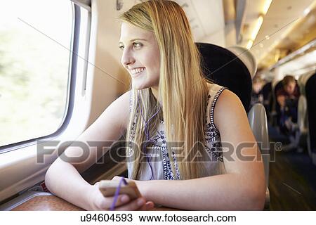 Stock Image - Teenage Girl Listening To Music On Train Journey. Fotosearch