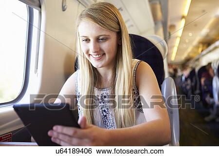 Stock Photograph - Teenage Girl Using Digital Tablet On Train Journey. Fotosearch