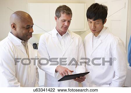 Stock Image - Three Doctors Having Discussion In American Hospital. Fotosearch