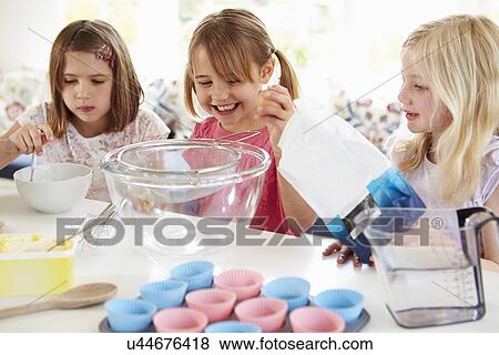 Stock Photo - Three Girls Making Cupcakes In Kitchen. Fotosearch