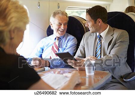 Stock Image - Two Businessmen Having Meeting On Train. Fotosearch