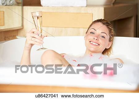 Stock Image - Woman Relaxing In Bath Drinking Champagne . Fotosearch