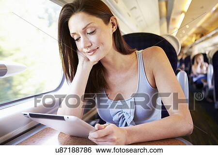 Stock Photograph - Woman Using Digital Tablet On Train. Fotosearch