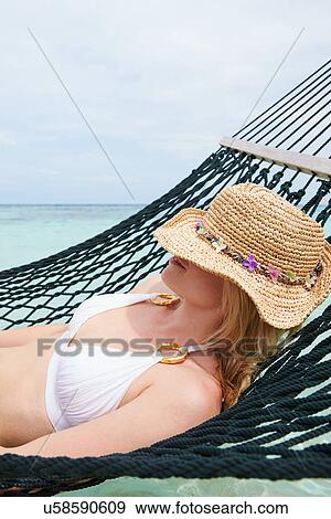 Stock Photo - Woman Wearing Bikini And Sun Hat Relaxing In Beach Hammock . Fotosearch