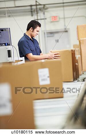 Stock Photography - Worker Checking Goods On Belt In Distribution Warehouse. Fotosearch