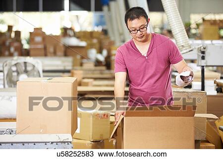 Stock Image - Worker In Warehouse Preparing Goods For Dispatch. Fotosearch