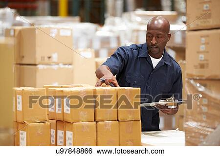 Stock Photograph - Worker In Warehouse Preparing Goods For Dispatch. Fotosearch