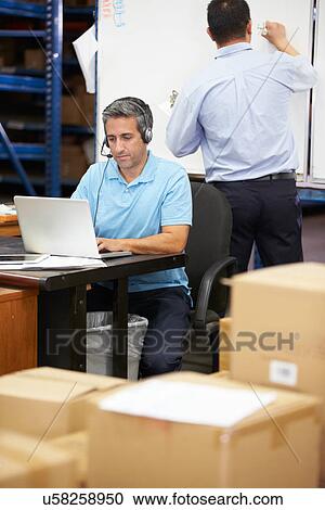 Worker In Warehouse Wearing Headset And Using Laptop View Large Photo Image Stock Image - Worker In Warehouse Wearing Headset And Using Laptop. Fotosearch