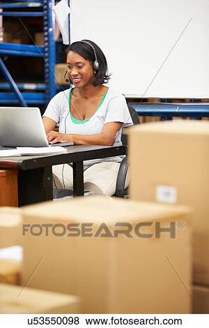 Worker In Warehouse Wearing Headset And Using Laptop View Large Photo Image Stock Photo - Worker In Warehouse Wearing Headset And Using Laptop. Fotosearch